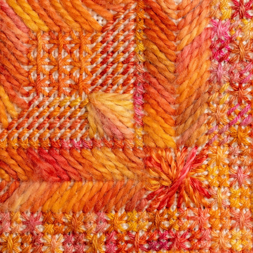 Close-up showing how over-dyed thread creates different colour effects in Rhodes stitch, cross stitch and gobelin — the same lavender thread pools and shifts differently in each stitch type