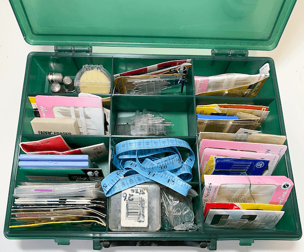 Repurposed plastic toolbox for neatly storing embroidery needles and sewing accessories.