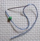 Step 1 - needle coming up through fabric with bead threaded on