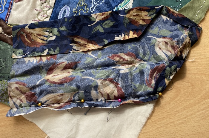Stitching the silk tie fabric into the corner of the crazy quilt block