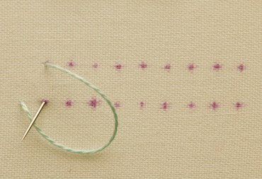 Blanket stitch step 2, needle going down with a loop of thread left on the surface
