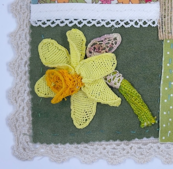 The needlelace daffodil displayed on a slow stitching piece