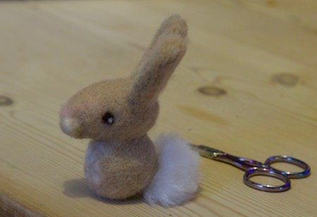 Finished needle felted bunny sitting on a neutral background
