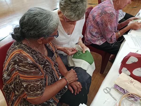 Two members of the South African craft club sharing and admiring Hardanger embroidery in progress