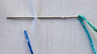 Herringbone stitch step 1 — first slanted stitch from bottom line to top line