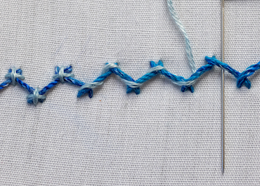 Laced herringbone stitch showing contrasting thread woven through diagonal stitches
