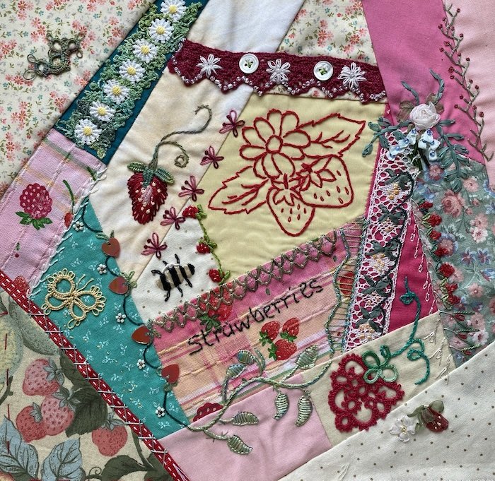 Completed crazy quilt block with strawberry fabric, embroidered seams and decorative stitches